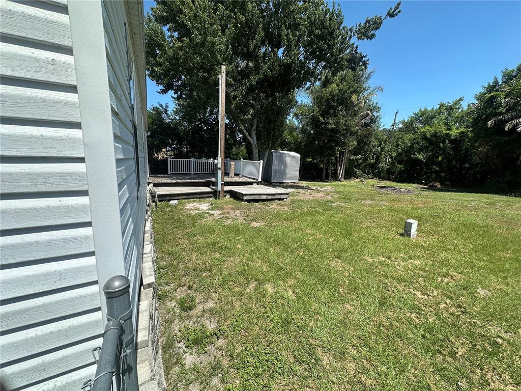 A backyard features a wooden deck, a small storage shed, and a grassy lawn — 2594 MCINTOSH DRIVE, LAKELAND, FL