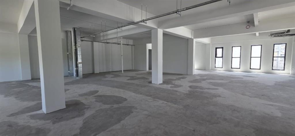 An unfinished commercial interior space features concrete floors, white support columns, and large windows — 656 RH TODD UNIT 3, SAN JUAN, PR