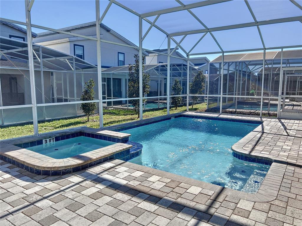 A screened-in patio features a rectangular swimming pool and a small attached hot tub — 831 STICKS STREET, DAVENPORT, FL