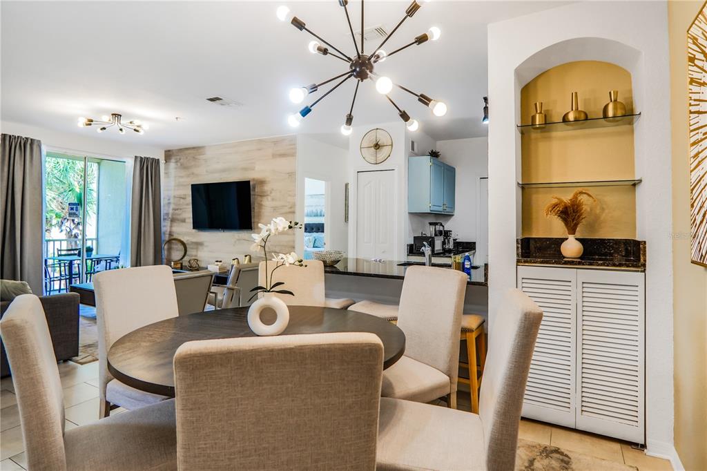 A dining area with a round table and chairs sits before an open kitchen — 8836 DUNES COURT UNIT 208, KISSIMMEE, FL