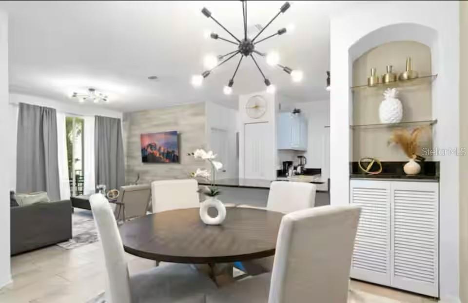 A dining area with a round table and chandelier opens into a living room — 8836 DUNES COURT UNIT 208, KISSIMMEE, FL