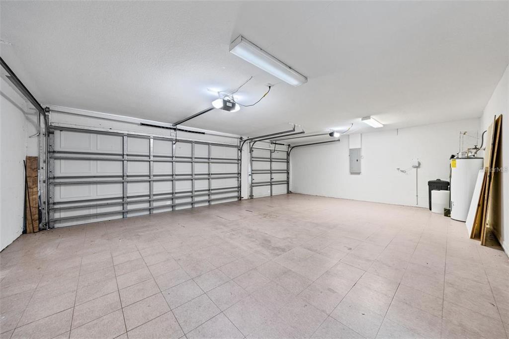 An empty two-car garage with white walls, tiled flooring, and two overhead garage doors — 1452 KENSINGTON WOODS DRIVE, LUTZ, FL