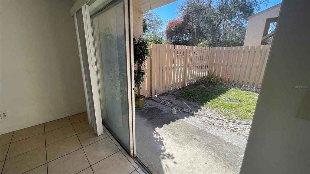 A tiled room opens through a sliding glass door to a fenced-in private backyard patio — 7502 NEEDLE LEAF PLACE UNIT 66, TAMPA, FL