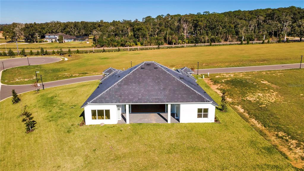 An aerial view shows the back of a white house with a dark hip roof — 35588 FARMVIEW ROAD, DADE CITY, FL