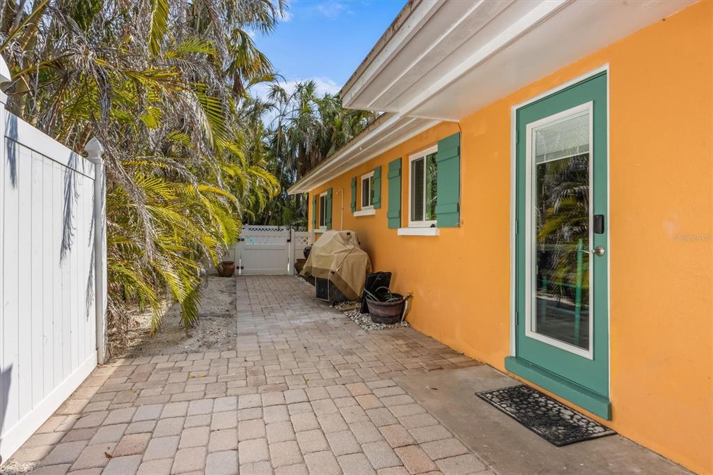 A paved side yard features an orange exterior wall, a green door, and palm trees — 5807 DE PALMAS AVENUE, HOLMES BEACH, FL