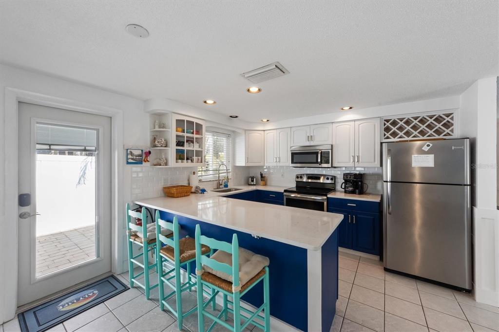 A kitchen features blue lower cabinets, white upper cabinets, a breakfast bar, and stainless appliances — 5807 DE PALMAS AVENUE, HOLMES BEACH, FL