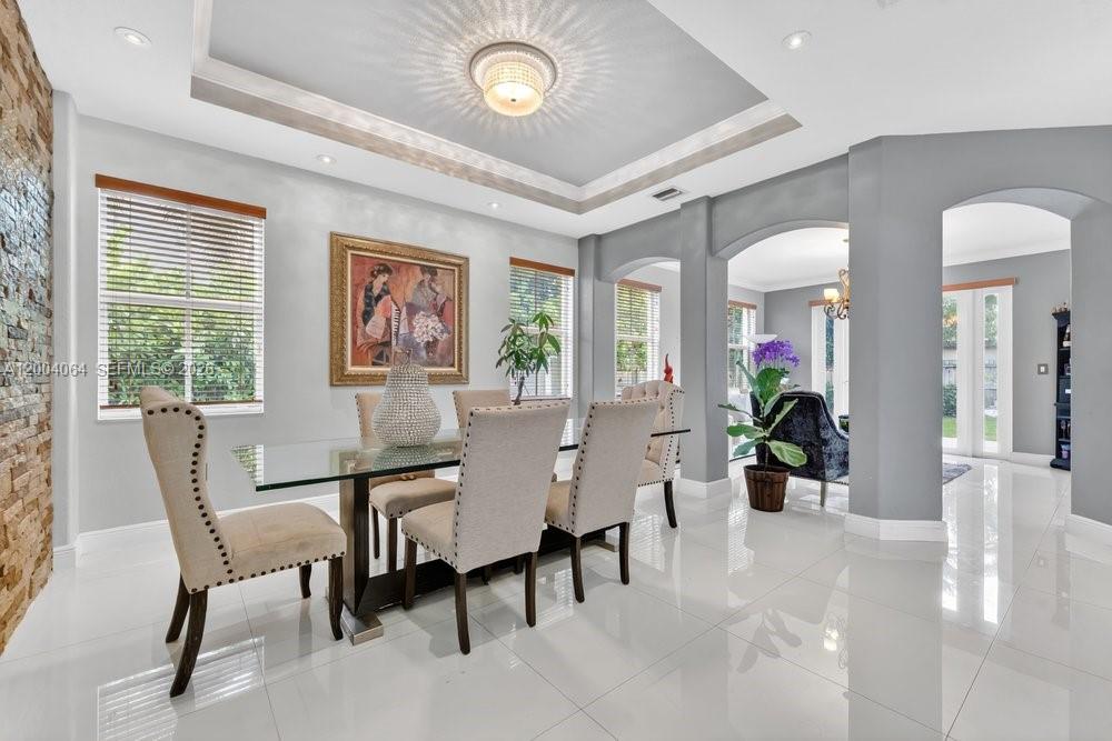 A dining room features a glass table, upholstered chairs, a tray ceiling, and tile flooring — 15465 SW 117th St, Miami FL 33196, MIAMI, FL
