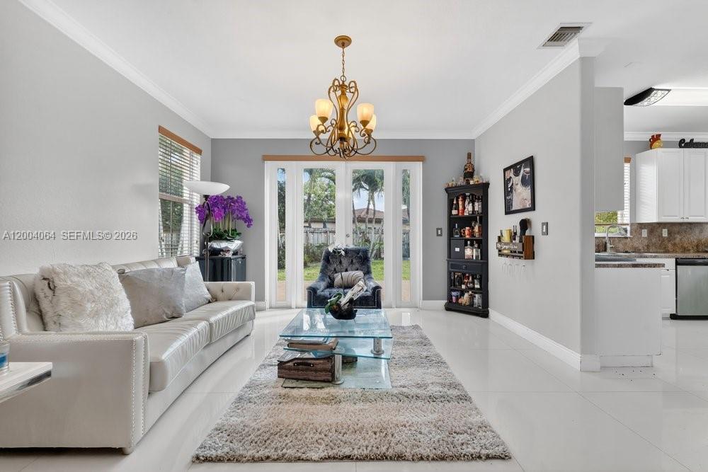 A living room with white tile floors, a glass coffee table, and a chandelier — 15465 SW 117th St, Miami FL 33196, MIAMI, FL