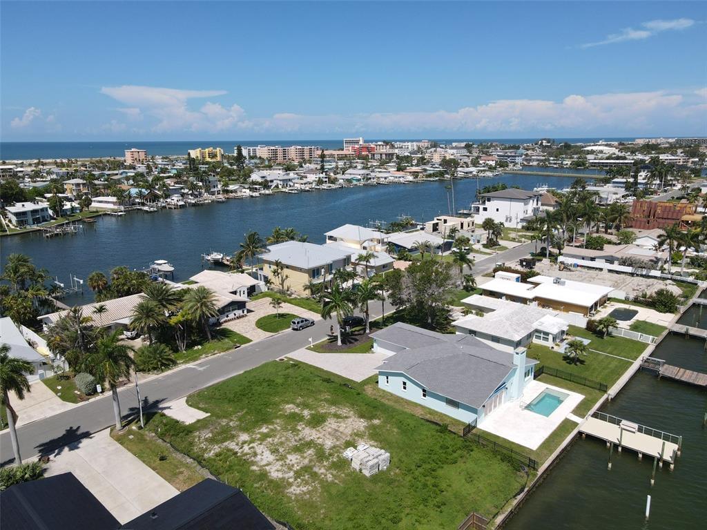 An aerial view shows a waterfront neighborhood with houses, swimming pools, and boat docks — 11125 4TH ST E, TREASURE ISLAND, FL