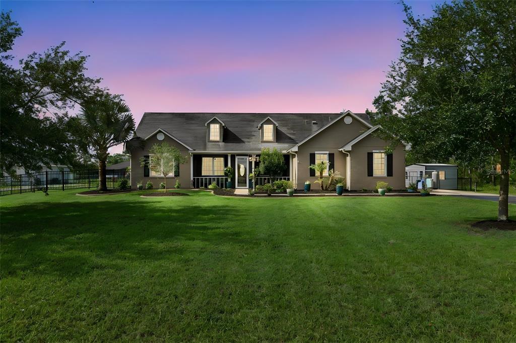 A single-story house with a dark roof and dormer windows sits behind a large lawn — 19204 PADDOCK STREET, ORLANDO, FL