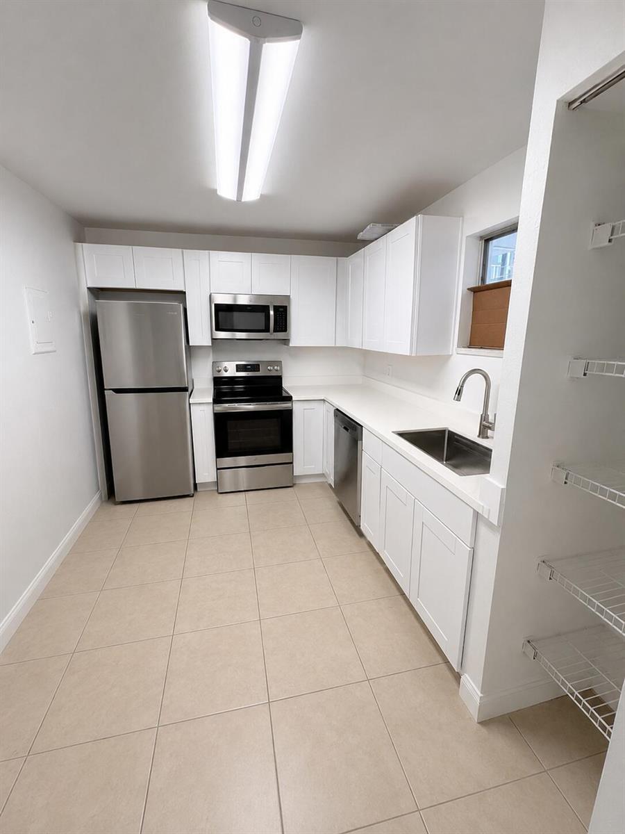 A kitchen features white cabinets, stainless steel appliances, a sink, and light-colored tile flooring — 4215 N University Drive # 112, Sunrise FL 33351, SUNRISE, FL