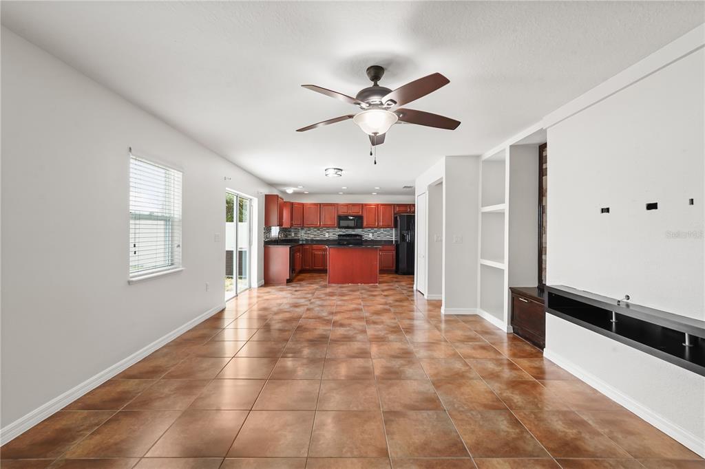 An open-concept living area with tile flooring leads to a kitchen with dark wood cabinets — 656 WASHINGTON WAY, HAINES CITY, FL