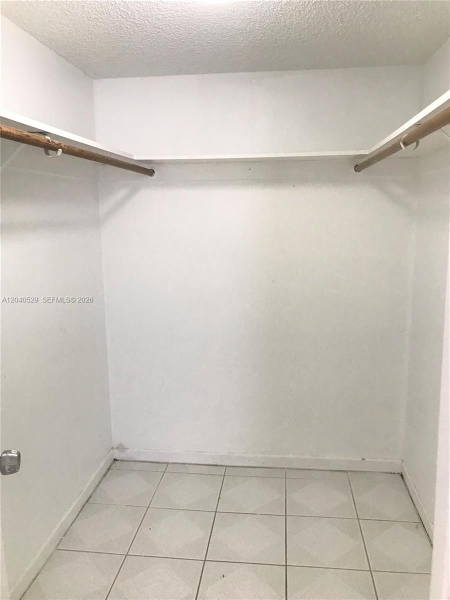 A walk-in closet features white walls, a tiled floor, and two wooden hanging rods — 10000 NW 80 Ct # 2537, Hialeah Gardens FL 33016, HIALEAH GARDENS, FL