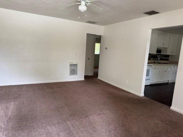 A carpeted living room leads to a kitchen with white cabinets and dark flooring — 2075 HOWELL BRANCH ROAD UNIT 101, MAITLAND, FL