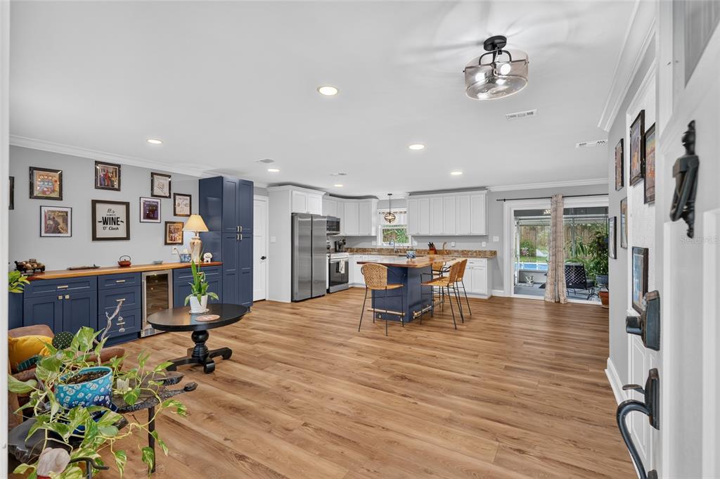 An open-concept kitchen features blue cabinetry, a central island, and wood-look flooring — 3862 NW 36TH PLACE, GAINESVILLE, FL