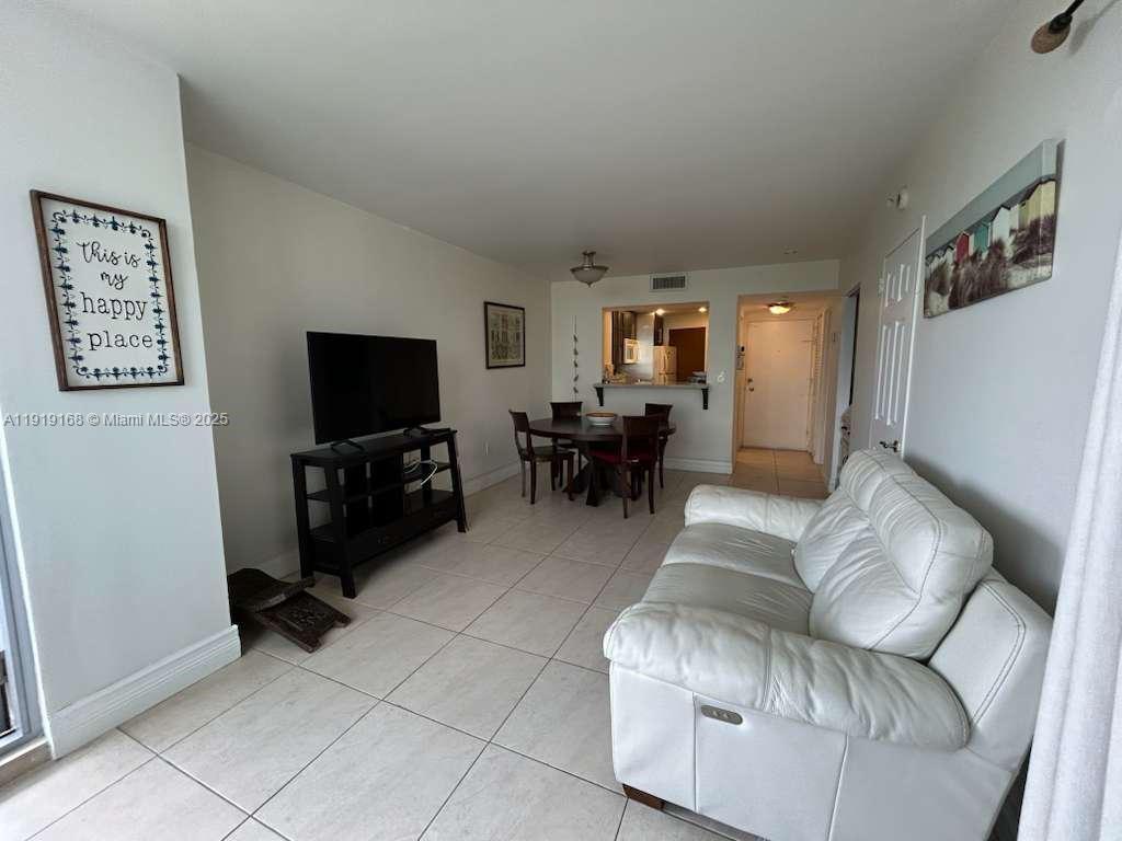 A living room and dining area feature white tile floors, a white sofa, and furniture — 2899 Collins Ave # 625, Miami Beach FL 33140, MIAMI BEACH, FL