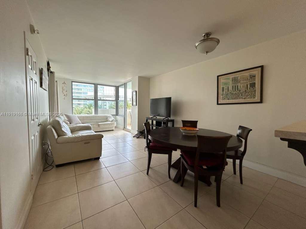 A living and dining area features tile flooring, a white sofa, and a round table — 2899 Collins Ave # 625, Miami Beach FL 33140, MIAMI BEACH, FL