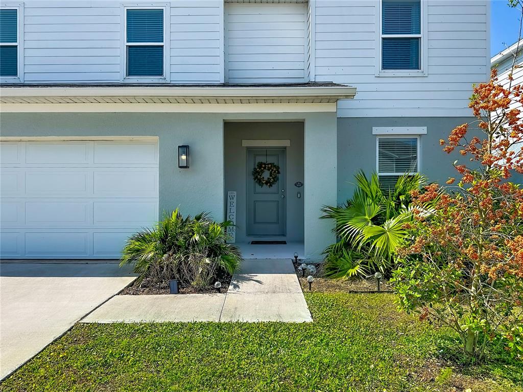A two-story house exterior features a gray front door, a garage, and landscaping — 13019 BLUFF OAK WAY, PARRISH, FL
