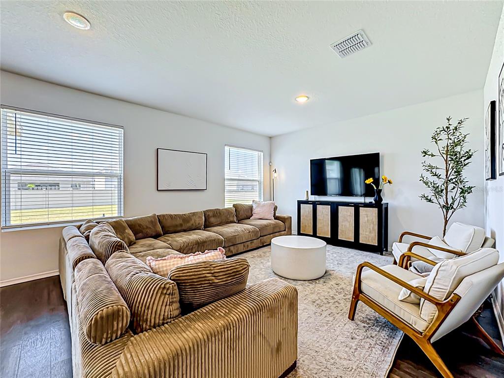 A living room features a large brown sectional sofa, two armchairs, and a television console — 13019 BLUFF OAK WAY, PARRISH, FL
