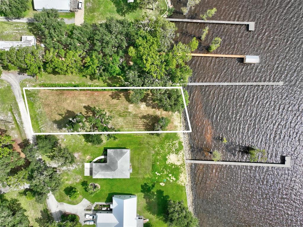 An aerial view shows a vacant, rectangular waterfront lot with trees next to existing homes — 100 SANDRA LANE, CRESCENT CITY, FL