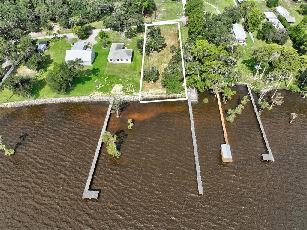 An aerial view shows a rectangular waterfront lot outlined in white with a private dock — 100 SANDRA LANE, CRESCENT CITY, FL