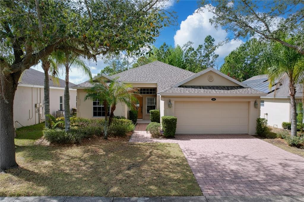 A single-story house with a beige stucco exterior, a two-car garage, and a paved driveway — 123 PRESTON AVENUE, DAVENPORT, FL