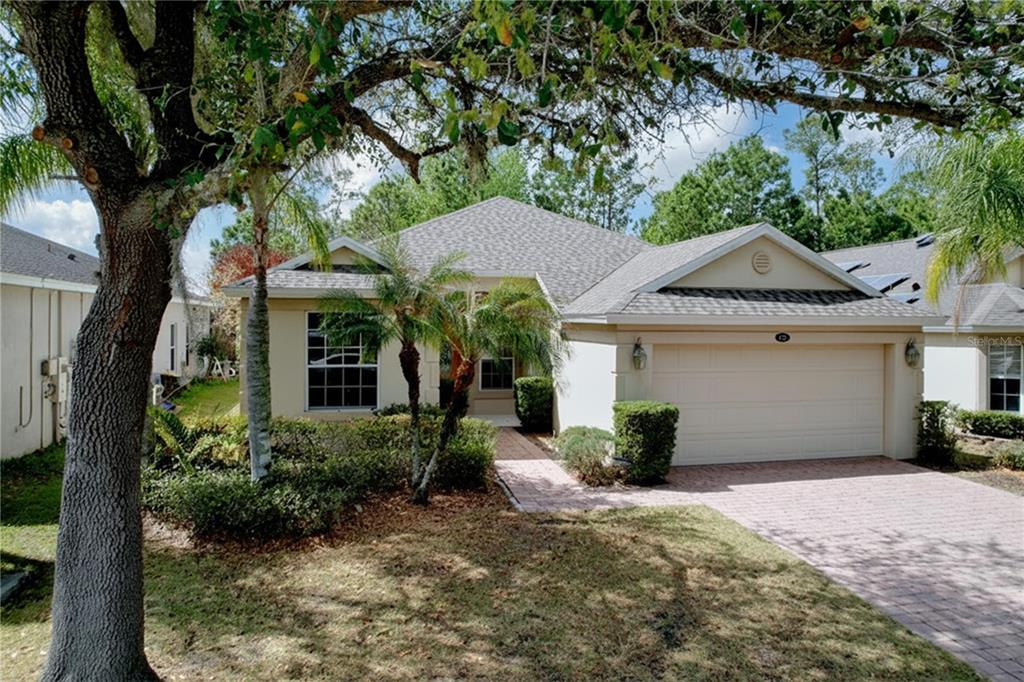 A single-story house with a beige exterior, a two-car garage, and a brick paver driveway — 123 PRESTON AVENUE, DAVENPORT, FL