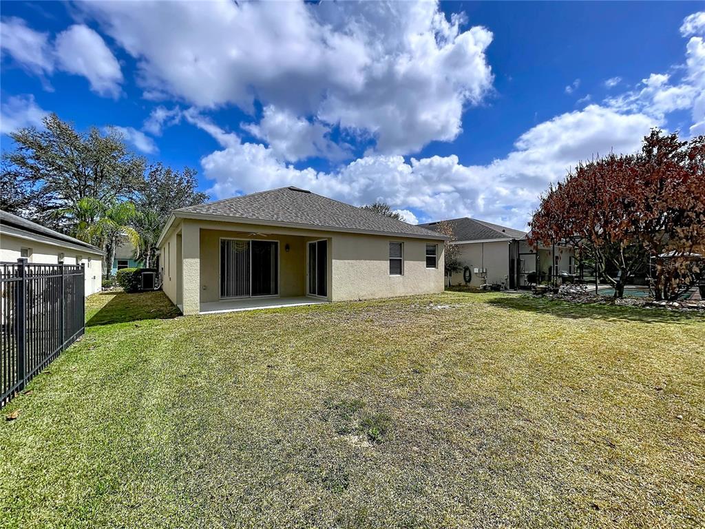 The exterior view shows the back of a beige house with a yard and fence — 123 PRESTON AVENUE, DAVENPORT, FL