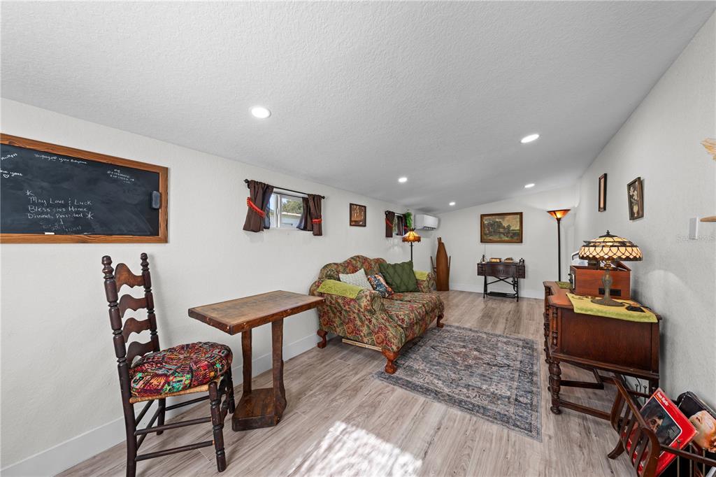 A living room features light wood-look flooring, a floral sofa, a wooden table, and a chalkboard — 1726 MISSOURI AVENUE, ST CLOUD, FL