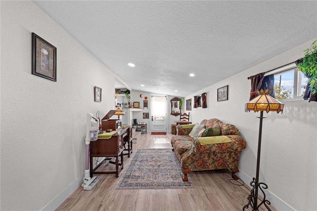 A living room features a floral sofa, a wooden desk, and a patterned area rug — 1726 MISSOURI AVENUE, ST CLOUD, FL