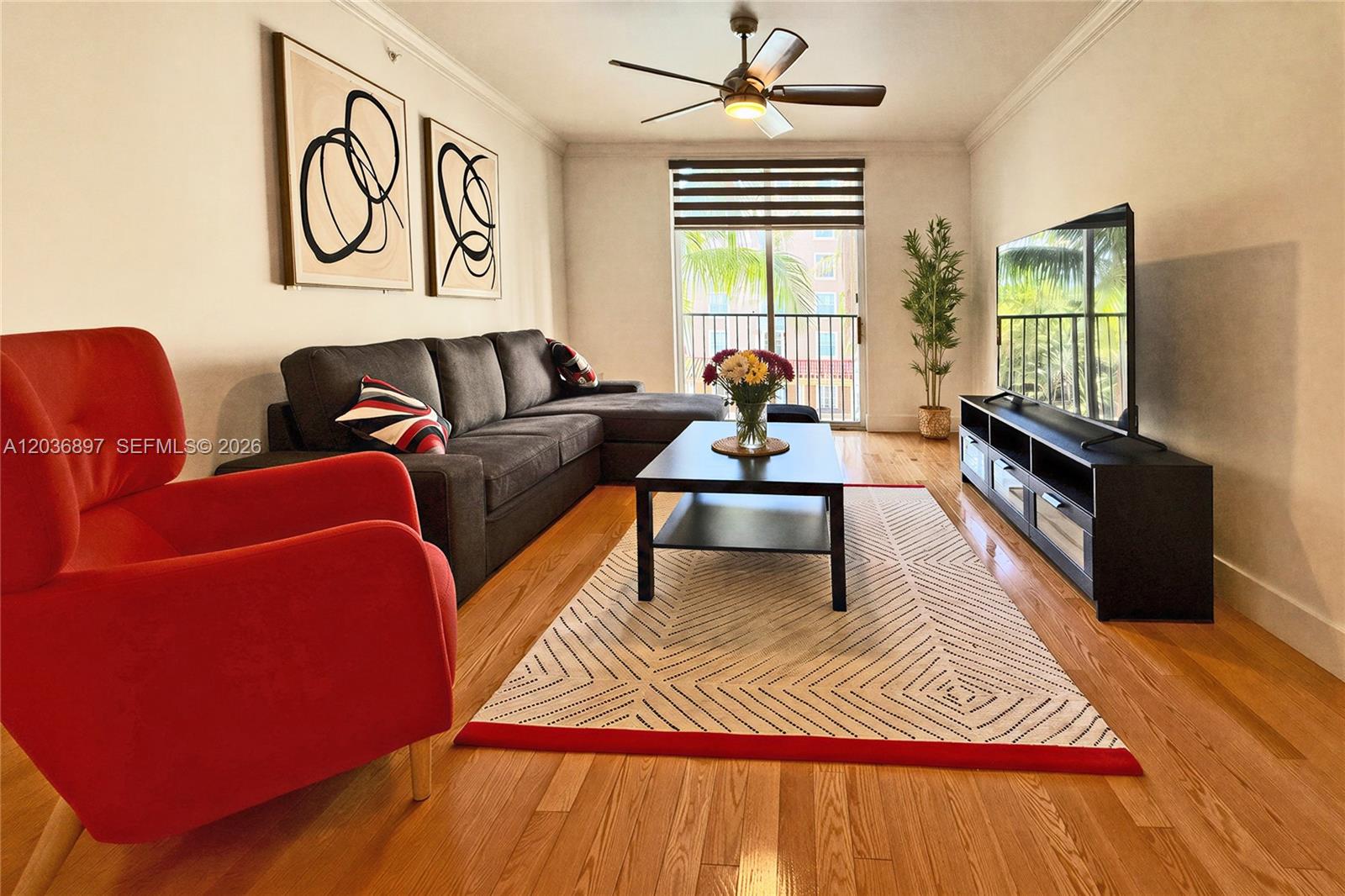 A living room features a red armchair, a dark sectional sofa, and a television console — 1900 Van Buren St # 317B, Hollywood FL 33020, HOLLYWOOD, FL