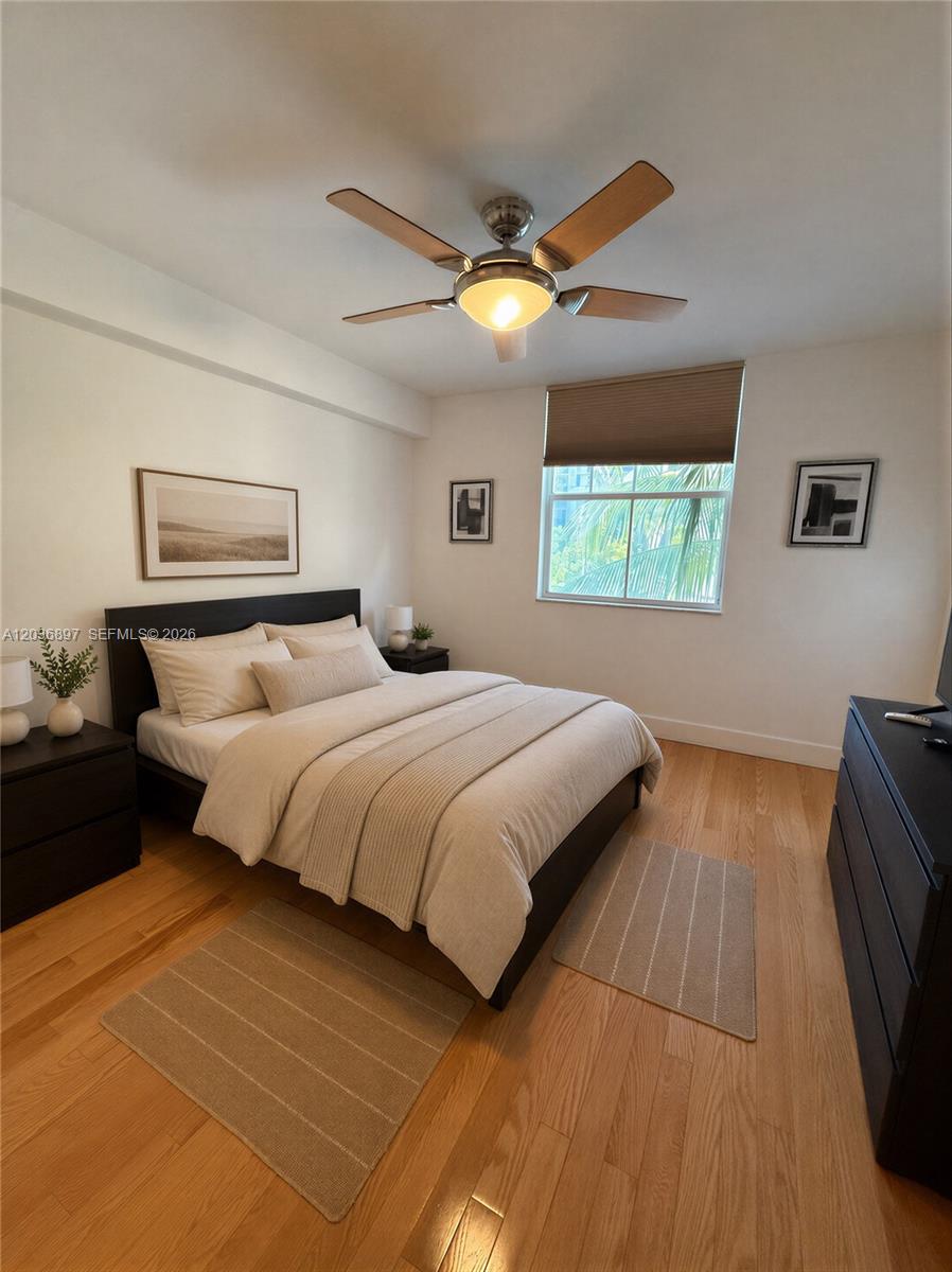 A bedroom features a bed with neutral bedding, a ceiling fan, and hardwood flooring — 1900 Van Buren St # 317B, Hollywood FL 33020, HOLLYWOOD, FL