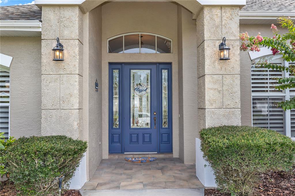 A blue front door with glass panels is centered between two stone-textured columns — 325 HAZELTINE DRIVE, DEBARY, FL