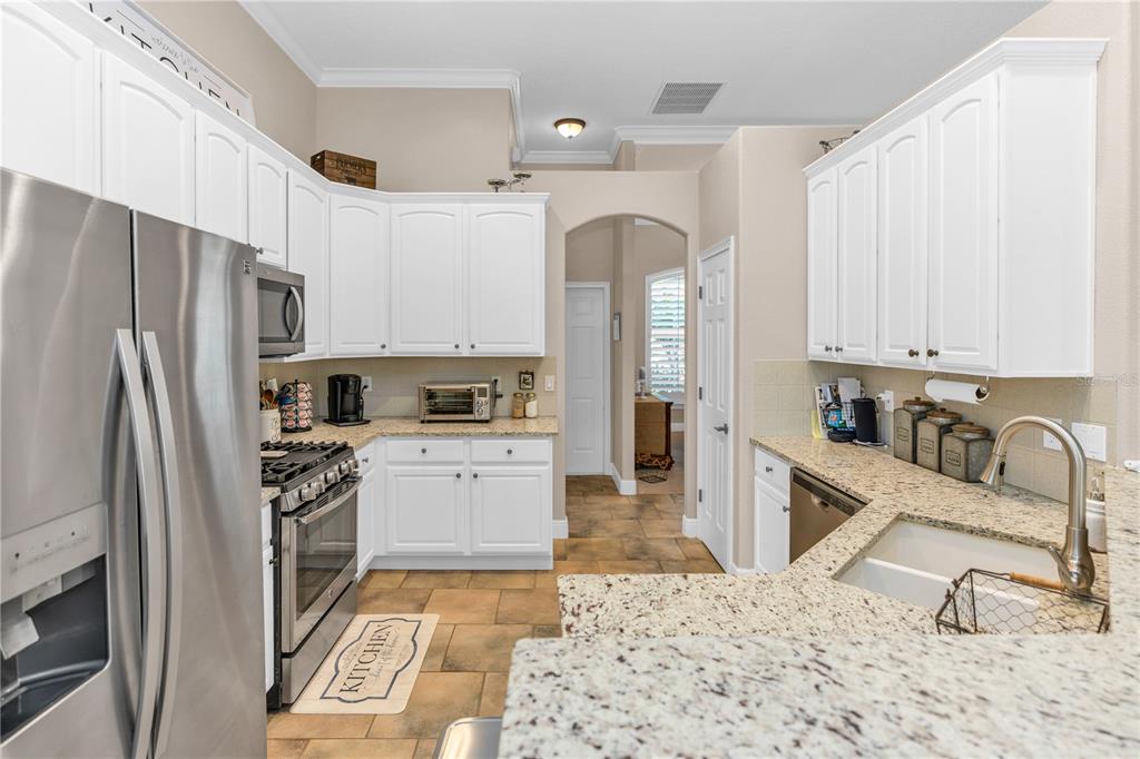 A kitchen with white cabinets, granite countertops, stainless steel appliances, and tile flooring — 325 HAZELTINE DRIVE, DEBARY, FL