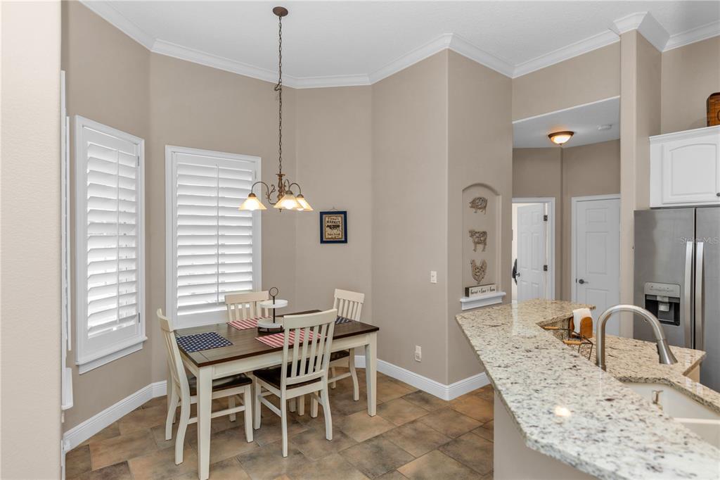 A dining area with a table, chairs, tile flooring, and an adjacent kitchen island — 325 HAZELTINE DRIVE, DEBARY, FL