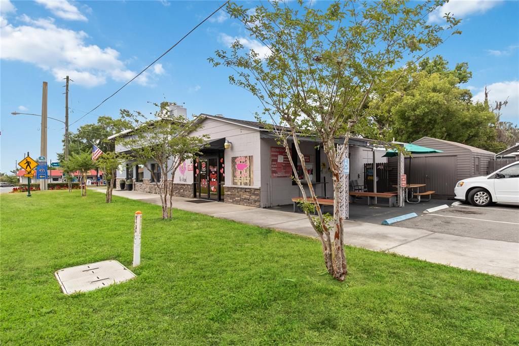 A single-story commercial building with a grassy lawn, outdoor seating, and a parking area — 17436 7TH STREET, MONTVERDE, FL