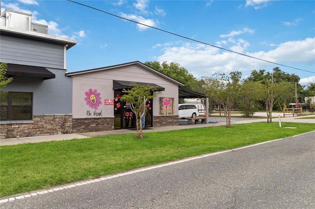 A single-story commercial building with a gray facade, stone base, and a flower mural — 17436 7TH STREET, MONTVERDE, FL
