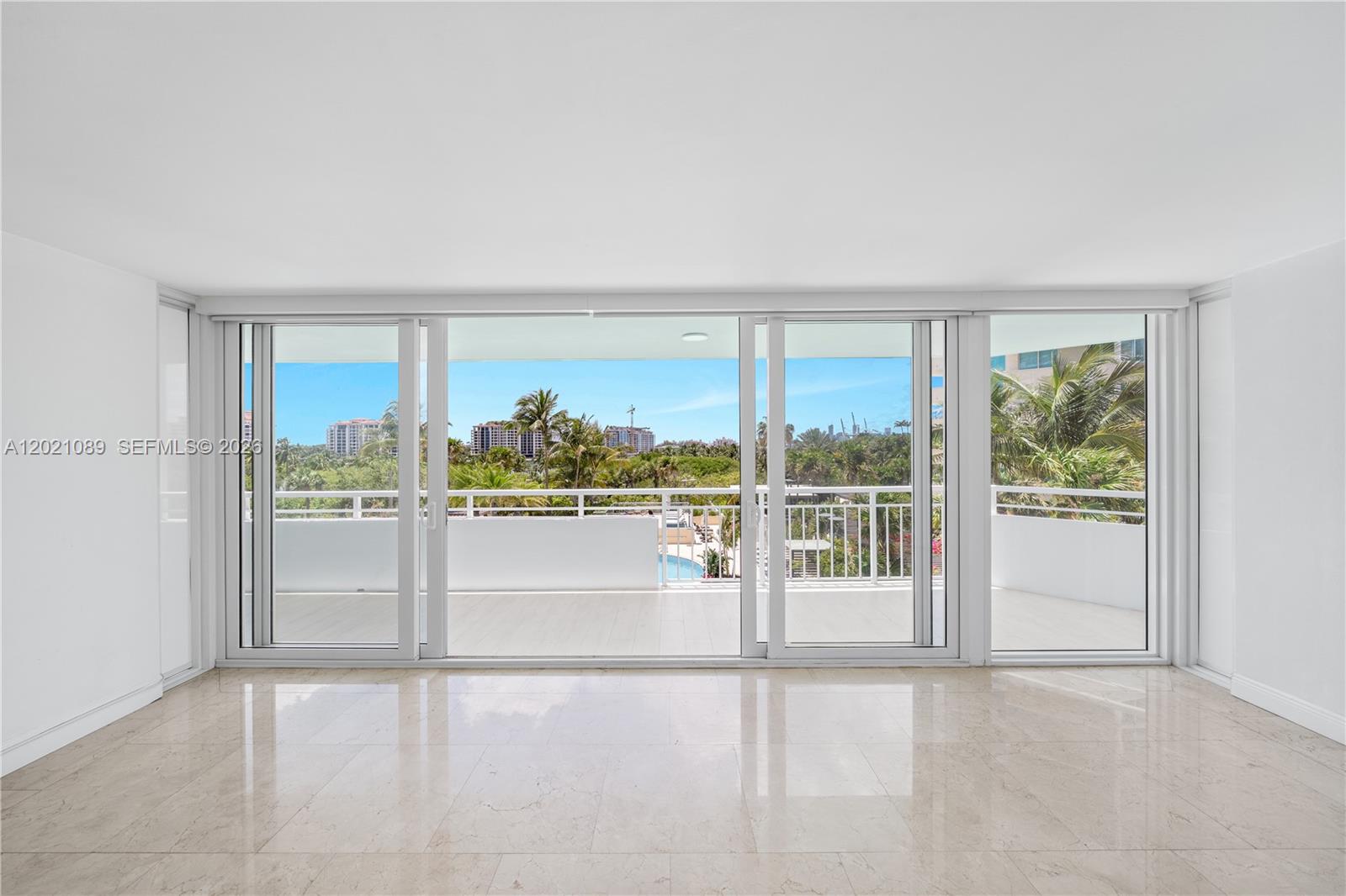 A bright, empty room features light-colored tile floors and large sliding glass doors to a balcony — 400 S Pointe Dr # 409, Miami Beach FL 33139, MIAMI BEACH, FL