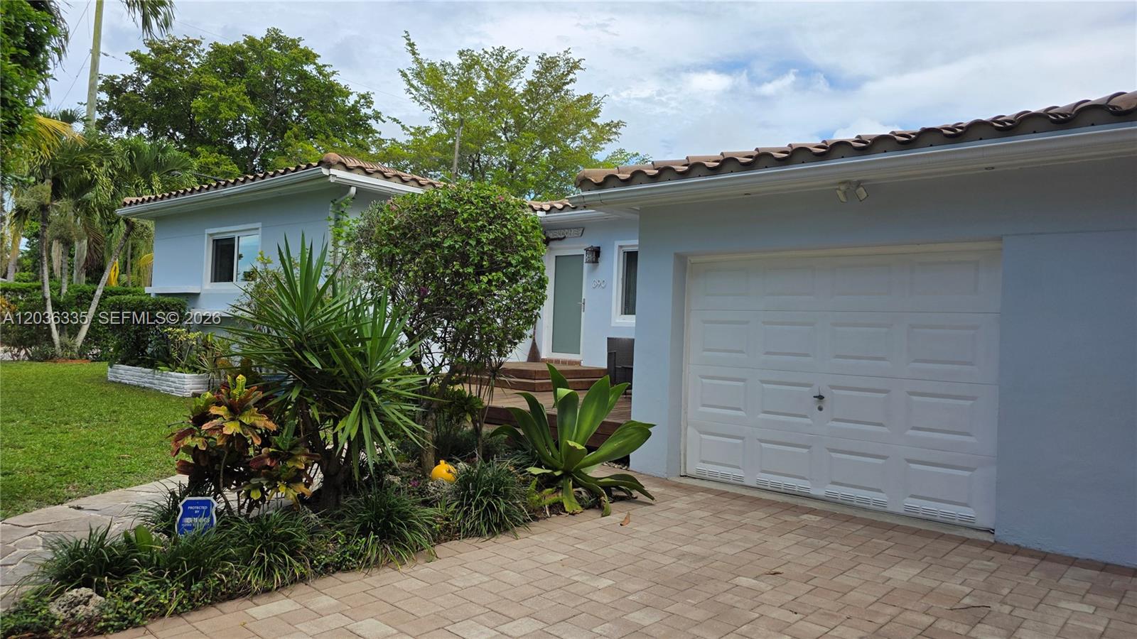 A wooden deck features a small seating area and a raised platform near a house — 390 NE 127th St, North Miami FL 33161, NORTH MIAMI, FL