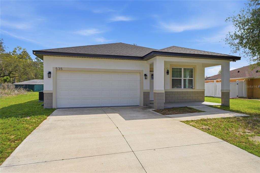 A single-story house with a white stucco exterior, a two-car garage, and a covered porch — 535 MARION OAKS LANE, OCALA, FL