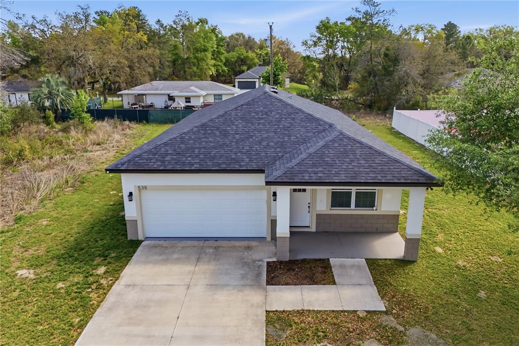 An aerial view of a single-story house with a dark roof and a concrete driveway — 535 MARION OAKS LANE, OCALA, FL