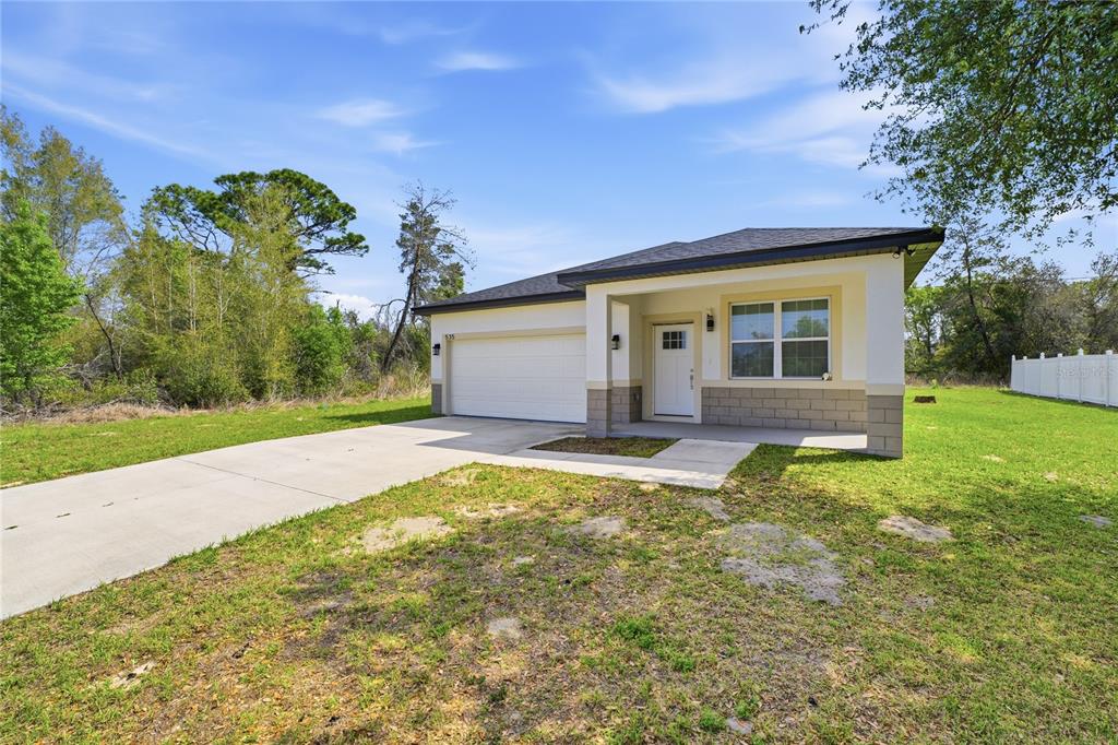 A single-story house with a white garage, a covered entryway, and a concrete driveway — 535 MARION OAKS LANE, OCALA, FL