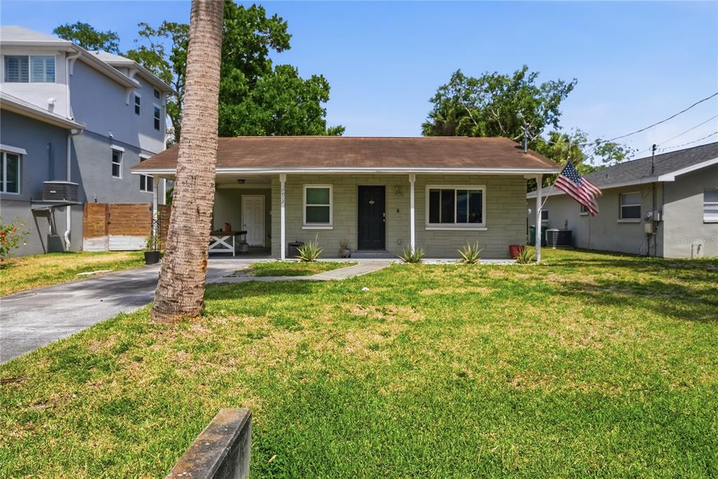 A single-story house with a light-colored brick facade, a covered porch, and a front lawn — 7412 S SHERRILL STREET, TAMPA, FL