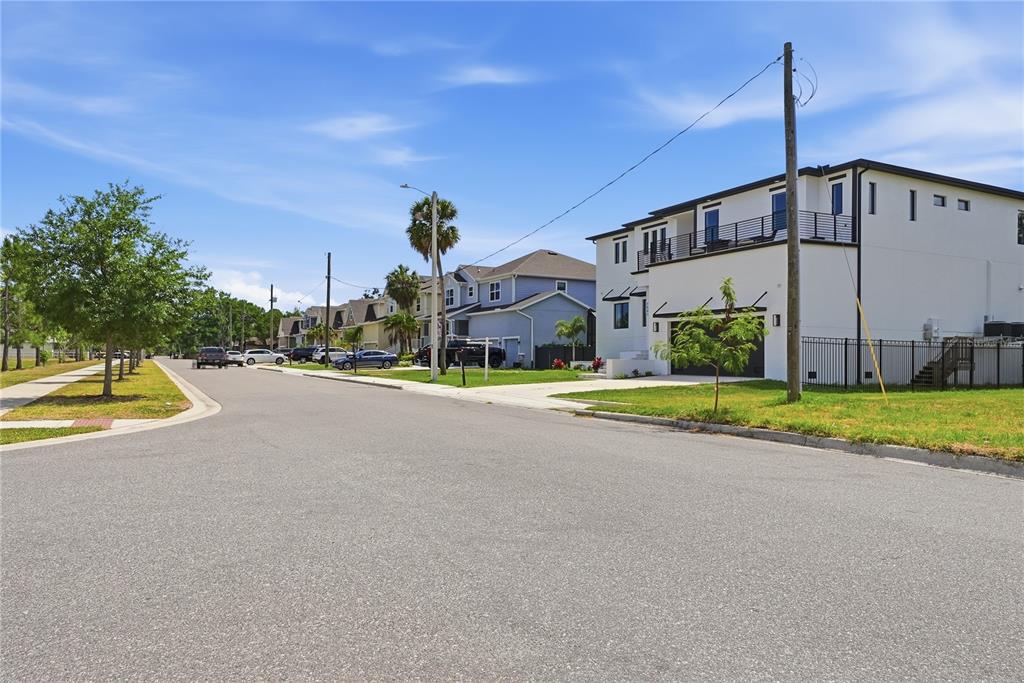 A street view showing a modern white house with a balcony next to suburban homes — 7412 S SHERRILL STREET, TAMPA, FL