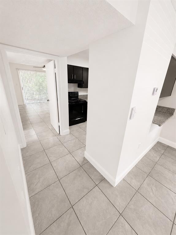A view from a tiled room looking into a kitchen with dark cabinets and appliances — 1185-1185 BENTLEY ROAD UNIT 4, LEESBURG, FL