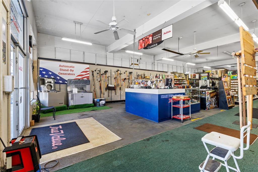 A retail hardware store interior features a central blue cashier counter and wall-mounted tools — 18493 HIGH SPRINGS MAIN STREET, HIGH SPRINGS, FL