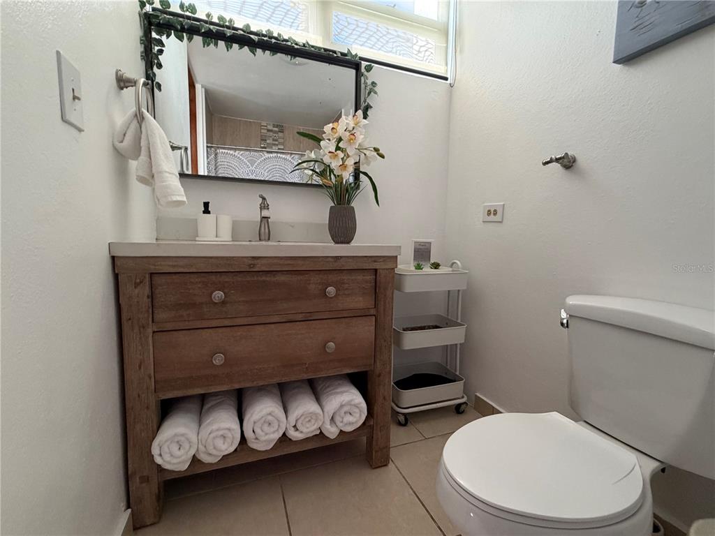 A bathroom features a wooden vanity with open towel storage, a mirror, and a toilet — 208 COND. VEREDAS DEL MAR UNIT 208, VEGA BAJA, PR
