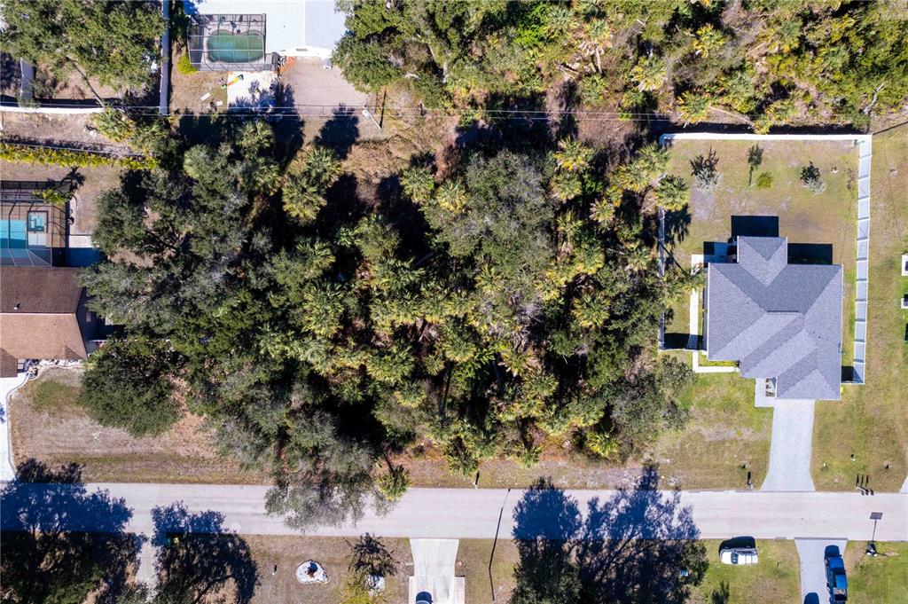 An aerial view shows a wooded vacant lot situated between two residential properties — 16250 BANYAN AVENUE, PORT CHARLOTTE, FL