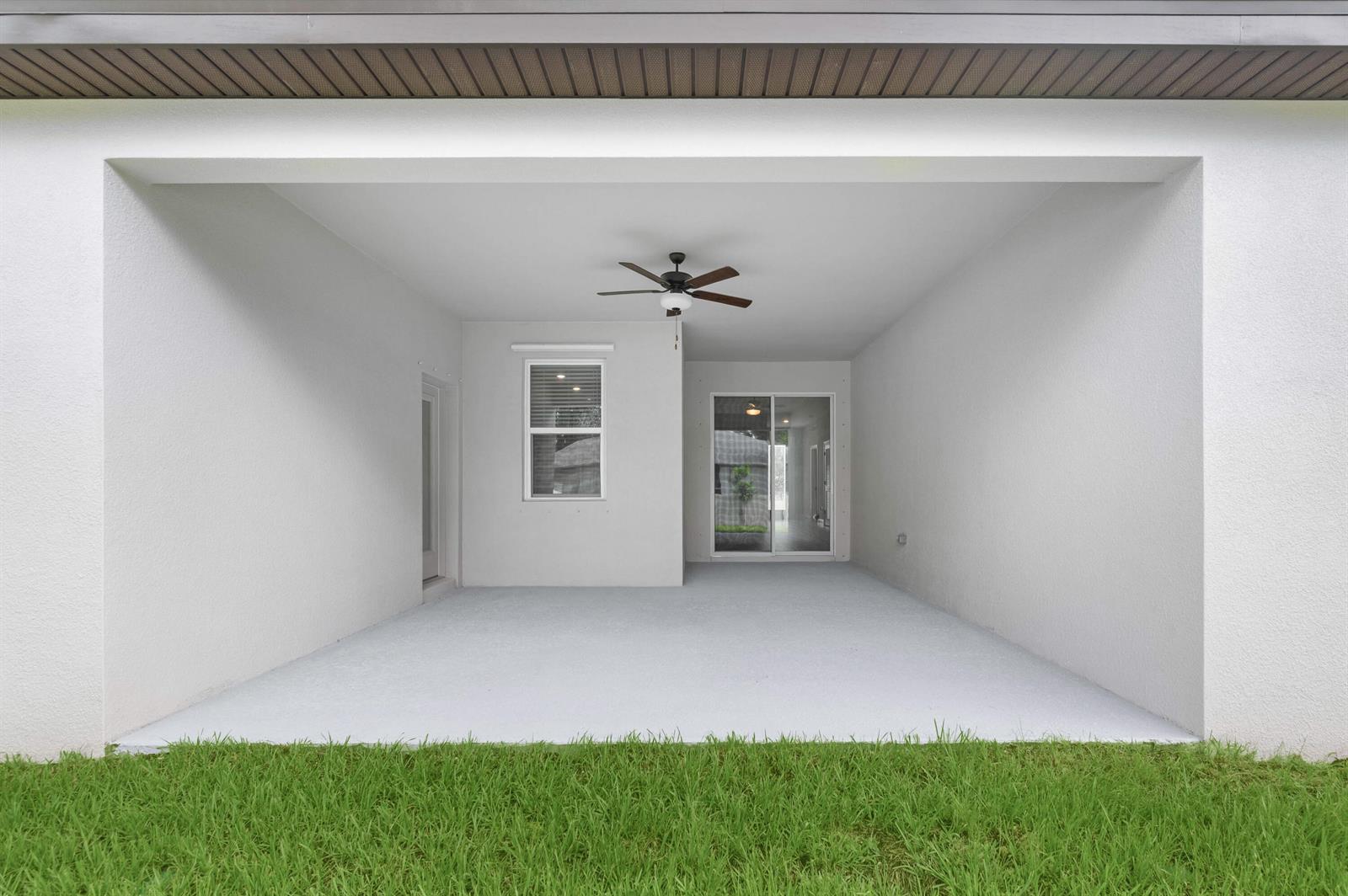 A covered concrete patio features a ceiling fan and sliding glass doors leading indoors — 9345 101st Avenue, Vero Beach FL 32967, VERO BEACH, FL
