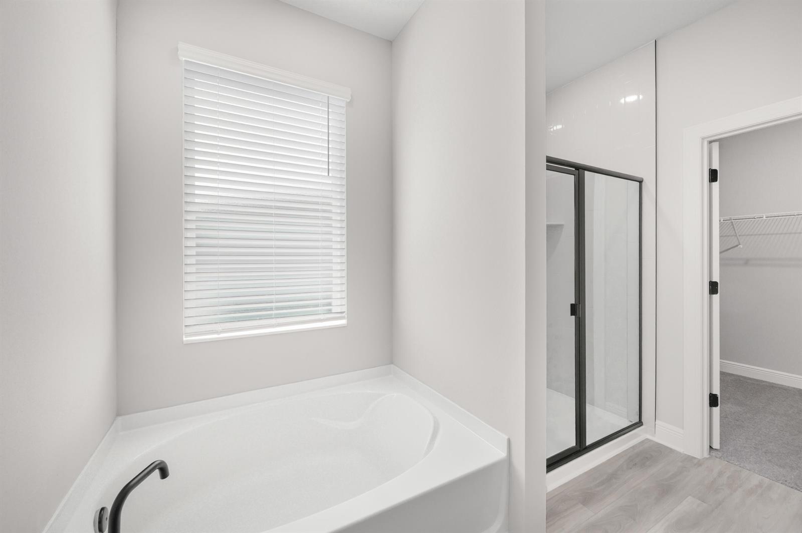 A bathroom features a white soaking tub, a glass-enclosed shower, and a walk-in closet — 9345 101st Avenue, Vero Beach FL 32967, VERO BEACH, FL